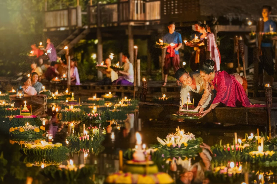 Thai locals in traditional costume release Krathong into the river to celebrate " Loy Krathong" festival.