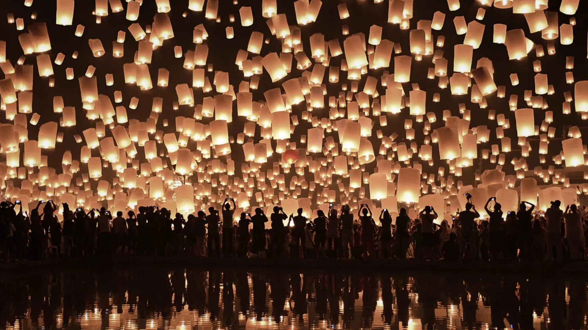 A local Thais watch Yi Peng lanterns floating into golden sky