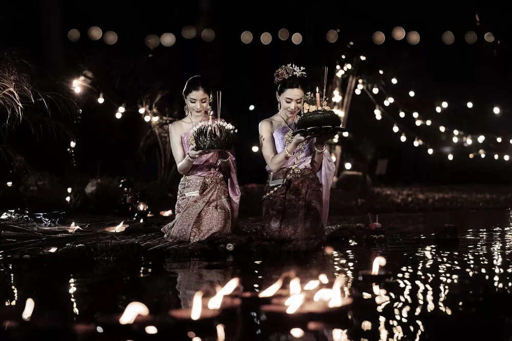 Thai locals in traditional costume release Krathong into the river